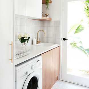 Foto di una sala lavanderia design con top in quarzo composito, top bianco, lavello da incasso, ante lisce, ante in legno chiaro, pareti bianche, lavasciuga e pavimento bianco