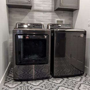 Foto di una piccola sala lavanderia bohémian con ante in stile shaker, ante grigie, paraspruzzi grigio, paraspruzzi con piastrelle in ceramica, pareti bianche, pavimento con piastrelle in ceramica, lavatrice e asciugatrice affiancate e pavimento multicolore