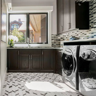 Idee per una grande sala lavanderia classica con lavello sottopiano, ante con riquadro incassato, ante in legno bruno, top in quarzo composito, paraspruzzi multicolore, paraspruzzi con piastrelle a listelli, pareti grigie, pavimento con piastrelle in ceramica, lavatrice e asciugatrice affiancate, pavimento bianco e top beige
