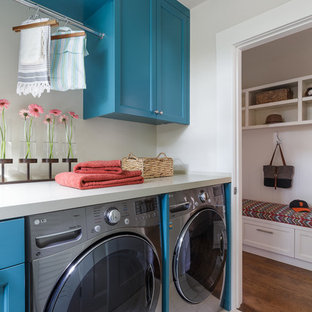 Inspiration pour une petit buanderie linéaire rustique dédiée avec des portes de placard bleues, un plan de travail en quartz modifié, un sol en carrelage de porcelaine, des machines côte à côte, un placard avec porte à panneau encastré et un mur gris.