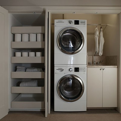 Inspiration for a small contemporary single-wall laundry closet remodel in San Francisco with a stacked washer/dryer, an undermount sink, flat-panel cabinets, beige cabinets and beige walls