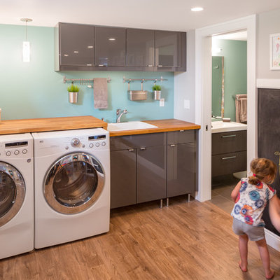 Example of a trendy laundry room design in Portland with gray cabinets, blue walls, wood countertops and brown countertops