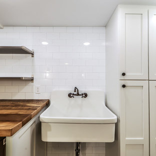 Idéer för att renovera ett mellanstort funkis brun brunt grovkök, med en allbänk, skåp i shakerstil, vita skåp, träbänkskiva, vita väggar, marmorgolv, en tvättmaskin och torktumlare bredvid varandra och svart golv