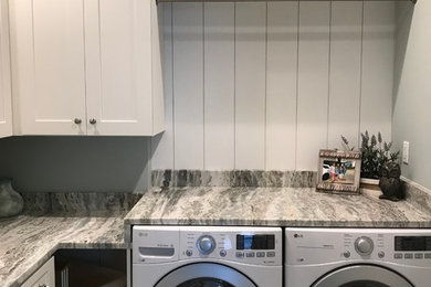 Mid-sized beach style l-shaped porcelain tile utility room photo in Jacksonville with shaker cabinets, white cabinets, granite countertops, gray walls, a side-by-side washer/dryer and gray countertops