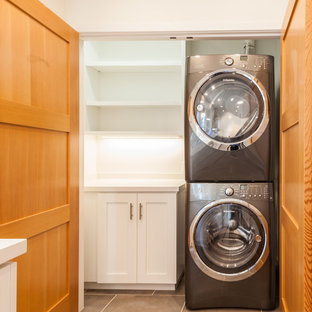 Immagine di una piccola sala lavanderia chic con ante in stile shaker, pareti bianche, pavimento in travertino, lavatrice e asciugatrice a colonna e ante bianche