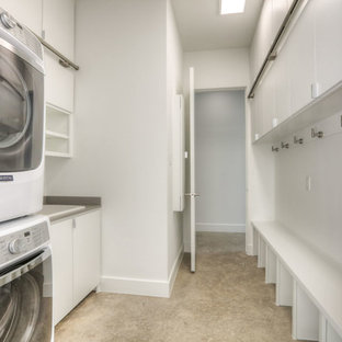 Modern inredning av ett mellanstort parallellt grovkök, med en nedsänkt diskho, släta luckor, vita skåp, vita väggar, betonggolv, en tvättpelare, beiget golv och laminatbänkskiva