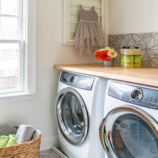 Exemple d'une buanderie chic dédiée et de taille moyenne avec un plan de travail en bois, un sol en carrelage de porcelaine, le lave-linge et le sèche-linge forment un seul appareil électroménager et un plan de travail marron.