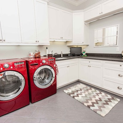 Inspiration for a timeless gray floor laundry room remodel in Orlando with white cabinets and an undermount sink