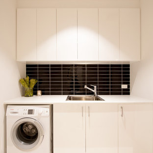 Réalisation d'une petit buanderie linéaire design dédiée avec un évier 1 bac, un placard à porte plane, des portes de placard blanches, un plan de travail en stratifié, un mur gris et un sol en carrelage de porcelaine.
