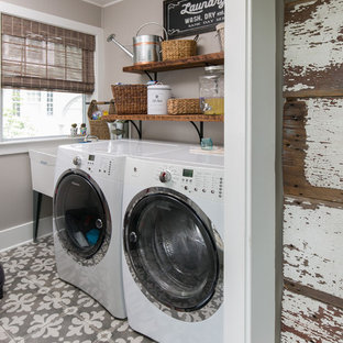 Immagine di una sala lavanderia country con lavatoio, lavatrice e asciugatrice affiancate, pavimento grigio e pareti grigie