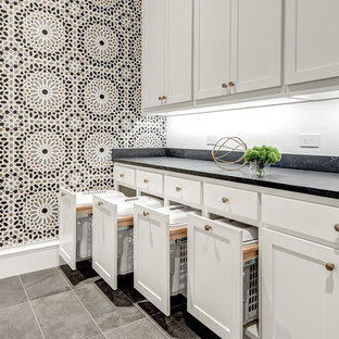 Immagine di una grande sala lavanderia mediterranea con lavello sottopiano, ante in stile shaker, ante bianche, top in granito, pareti bianche, lavatrice e asciugatrice affiancate, top nero, pavimento in gres porcellanato e pavimento grigio