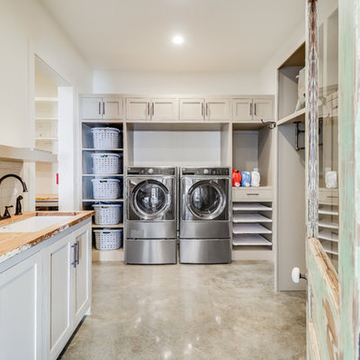 Utility room - country u-shaped concrete floor and gray floor utility room idea in Jackson with an undermount sink, shaker cabinets, beige cabinets, wood countertops, white walls, a side-by-side washer/dryer and beige countertops