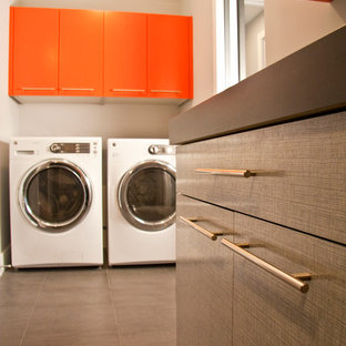 Bild på en liten funkis svarta linjär svart tvättstuga enbart för tvätt, med släta luckor, orange skåp, laminatbänkskiva och en tvättmaskin och torktumlare bredvid varandra