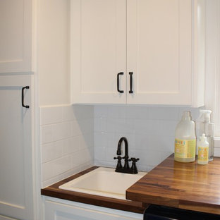 Foto di una piccola lavanderia multiuso stile americano con lavello sottopiano, ante in stile shaker, ante bianche, top in legno, pareti grigie, pavimento in gres porcellanato e lavatrice e asciugatrice affiancate