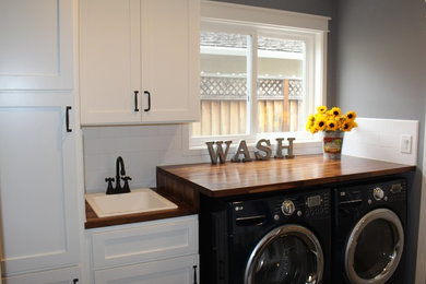 Small traditional utility room in San Francisco with shaker cabinets, white cabinets, wood worktops, grey walls, porcelain flooring, a side by side washer and dryer, brown worktops and a built-in sink.