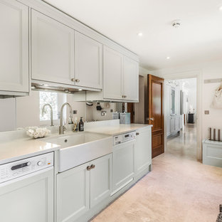 Design ideas for a traditional l-shaped utility room in Berkshire with a belfast sink, recessed-panel cabinets, grey cabinets, white walls, beige floors and white worktops.
