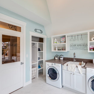 Foto di una lavanderia multiuso stile marinaro con lavello da incasso, ante in stile shaker, ante bianche, top in legno, pareti blu, lavatrice e asciugatrice affiancate e top marrone
