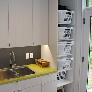 Ispirazione per una sala lavanderia contemporanea di medie dimensioni con lavello a doppia vasca, ante lisce, ante grigie, top in laminato, pareti grigie, pavimento in legno massello medio, lavatrice e asciugatrice affiancate, pavimento grigio e top giallo
