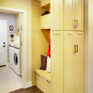 Immagine di una sala lavanderia chic di medie dimensioni con ante in stile shaker, ante gialle, top in quarzo composito, parquet scuro, lavatrice e asciugatrice affiancate e pareti beige
