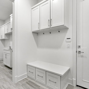Exemple d'une buanderie chic avec un évier encastré, un placard à porte shaker, des portes de placard blanches, un plan de travail en onyx, un mur blanc, un sol en carrelage de porcelaine, des machines côte à côte, un sol gris et un plan de travail blanc.