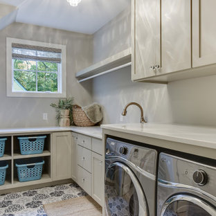 Réalisation d'une buanderie champêtre en L dédiée et de taille moyenne avec un évier posé, un placard à porte shaker, des portes de placard grises, un plan de travail en quartz modifié, un mur beige, un sol en carrelage de porcelaine, des machines côte à côte, un sol bleu et un plan de travail beige.