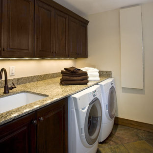 Ispirazione per una grande sala lavanderia classica con lavello sottopiano, ante con bugna sagomata, ante in legno bruno, top in granito, pareti beige, pavimento in ardesia e lavatrice e asciugatrice affiancate