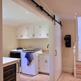 Ispirazione per una lavanderia multiuso chic di medie dimensioni con lavello sottopiano, ante bianche, pavimento in travertino, lavatrice e asciugatrice affiancate, pavimento beige, ante in stile shaker, top in superficie solida e pareti beige