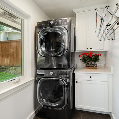 Mid-sized transitional single-wall porcelain tile and gray floor dedicated laundry room photo in Dallas with white cabinets, quartz countertops, white walls, a stacked washer/dryer, white countertops and shaker cabinets