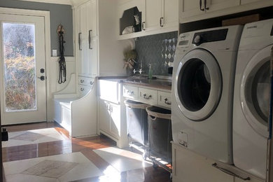 Inspiration for a large craftsman single-wall medium tone wood floor and multicolored floor utility room remodel in Other with a farmhouse sink, shaker cabinets, white cabinets, wood countertops, gray walls and a side-by-side washer/dryer