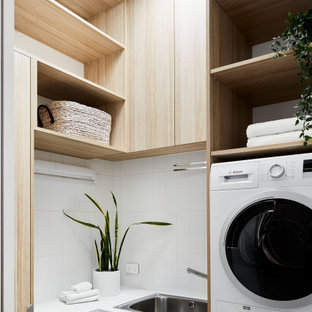 Foto di una piccola sala lavanderia design con lavello da incasso, ante a filo, ante in legno chiaro, top in marmo, pareti bianche, pavimento con piastrelle in ceramica, lavatrice e asciugatrice a colonna, pavimento bianco e top bianco