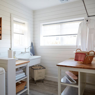 Esempio di una grande sala lavanderia stile marino con lavello stile country, nessun'anta, ante bianche, top in legno, pareti bianche, pavimento in laminato, lavatrice e asciugatrice affiancate, pavimento grigio e pareti in perlinato