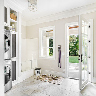 Idee per una grande lavanderia multiuso classica con ante bianche, pareti beige, pavimento con piastrelle in ceramica, lavatrice e asciugatrice a colonna e pavimento grigio