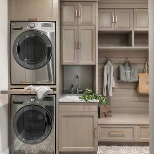 Idee per una lavanderia multiuso classica di medie dimensioni con ante con riquadro incassato, ante grigie, top in quarzite, paraspruzzi grigio, paraspruzzi in lastra di pietra, top grigio, lavello sottopiano, pareti beige, lavatrice e asciugatrice a colonna e pavimento beige