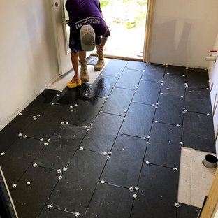 Esempio di una sala lavanderia bohémian con ante marroni, top in quarzite, pareti beige, pavimento con piastrelle in ceramica, lavatrice e asciugatrice affiancate, pavimento nero e top bianco