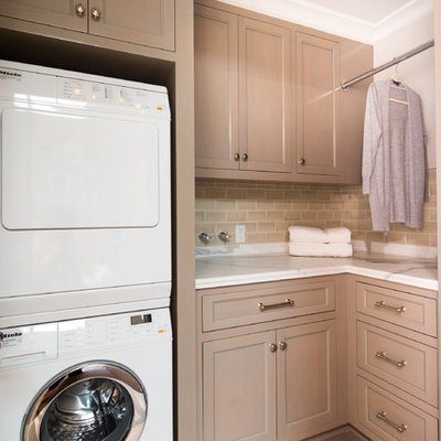 Example of a small classic l-shaped laundry room design in Los Angeles with recessed-panel cabinets, light wood cabinets, white walls, a stacked washer/dryer and white countertops
