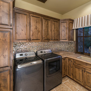 Foto di un'ampia sala lavanderia classica con lavello da incasso, ante con riquadro incassato, ante in legno scuro, top in granito, pareti beige, pavimento in travertino e lavatrice e asciugatrice affiancate