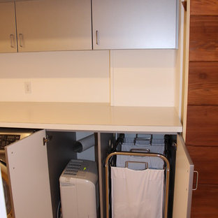 Idéer för stora funkis linjära grovkök, med en enkel diskho, släta luckor, skåp i rostfritt stål, laminatbänkskiva, vita väggar, ljust trägolv och en tvättmaskin och torktumlare bredvid varandra