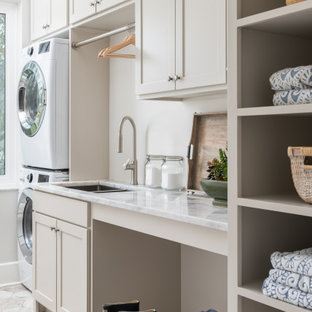 Ispirazione per una sala lavanderia country di medie dimensioni con lavello sottopiano, ante in stile shaker, ante beige, top in marmo, pareti bianche, pavimento in gres porcellanato, lavatrice e asciugatrice a colonna, pavimento beige e top bianco