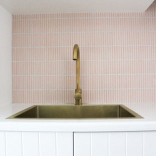 Esempio di una sala lavanderia moderna di medie dimensioni con lavello da incasso, ante in stile shaker, ante bianche, top in quarzo composito, paraspruzzi rosa, paraspruzzi con piastrelle a mosaico, pareti bianche, pavimento in gres porcellanato, lavatrice e asciugatrice a colonna, pavimento bianco e top bianco