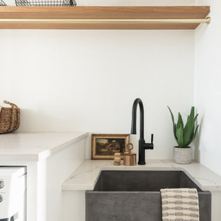 Exempel på en stor modern beige parallell beige tvättstuga enbart för tvätt, med en rustik diskho, vita skåp, vita väggar och ljust trägolv