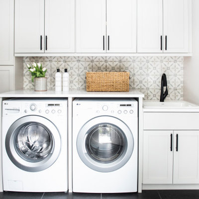 Dedicated laundry room - transitional single-wall black floor dedicated laundry room idea in Boston with a drop-in sink, shaker cabinets, white cabinets, gray walls, a side-by-side washer/dryer and white countertops