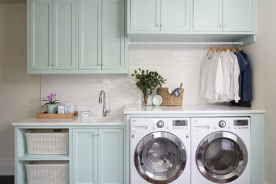 Mid-sized elegant single-wall dark wood floor and brown floor dedicated laundry room photo in Nashville with an undermount sink, turquoise cabinets, quartz countertops, a side-by-side washer/dryer, white countertops, recessed-panel cabinets and beige walls