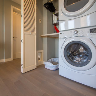 Laundry closet - small transitional single-wall medium tone wood floor laundry closet idea in Seattle with solid surface countertops, a stacked washer/dryer and gray walls