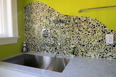 Inredning av ett modernt stort flerfärgad linjärt flerfärgat grovkök, med en allbänk, släta luckor, vita skåp, bänkskiva i kalksten, gröna väggar, vinylgolv, en tvättmaskin och torktumlare bredvid varandra och flerfärgat golv