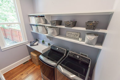 Inspiration for a mid-sized single-wall medium tone wood floor dedicated laundry room remodel in Atlanta with open cabinets, white cabinets, laminate countertops, gray walls, a side-by-side washer/dryer and white countertops