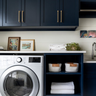 Idées déco pour une grand buanderie parallèle classique dédiée avec un évier encastré, un placard à porte shaker, des portes de placard bleues, un plan de travail en quartz modifié, une crédence en lambris de bois, un mur blanc, un sol en carrelage de porcelaine, des machines côte à côte, un sol multicolore, un plan de travail blanc et du lambris de bois.