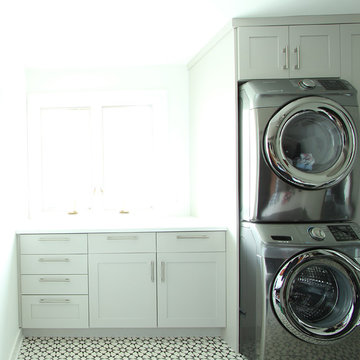 Grey Painted Cabinets in Laundry Room with Stacked Washer and Dryer