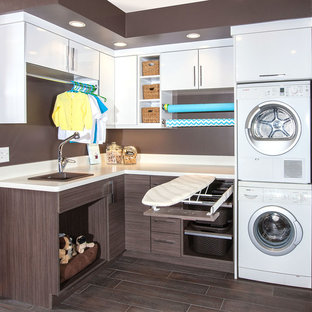 Inspiration pour une buanderie design en L multi-usage et de taille moyenne avec un évier posé, un placard à porte plane, des portes de placard blanches, un plan de travail en stratifié, un mur marron, un sol en carrelage de porcelaine et des machines superposées.