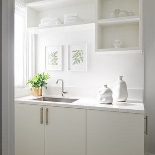 Laundry closet - large transitional single-wall light wood floor laundry closet idea in San Francisco with an undermount sink, flat-panel cabinets, white cabinets, quartz countertops, white walls, a stacked washer/dryer and white countertops