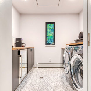 Ispirazione per una piccola sala lavanderia moderna con lavello da incasso, ante lisce, ante nere, top in legno, pareti bianche, pavimento con piastrelle in ceramica, lavatrice e asciugatrice affiancate e pavimento multicolore